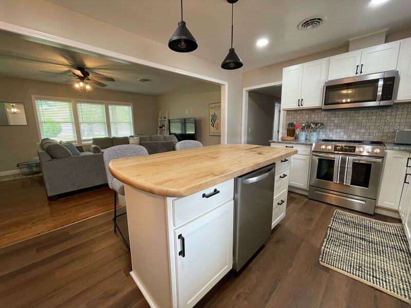 The open plan seen from the kitchen: the live-edge island in the foreground and the living room beyond, with no wall between them.